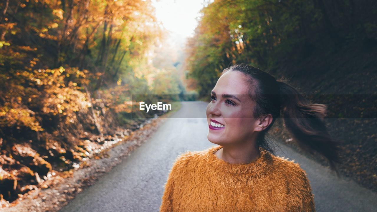 Smiling young woman standing on road 