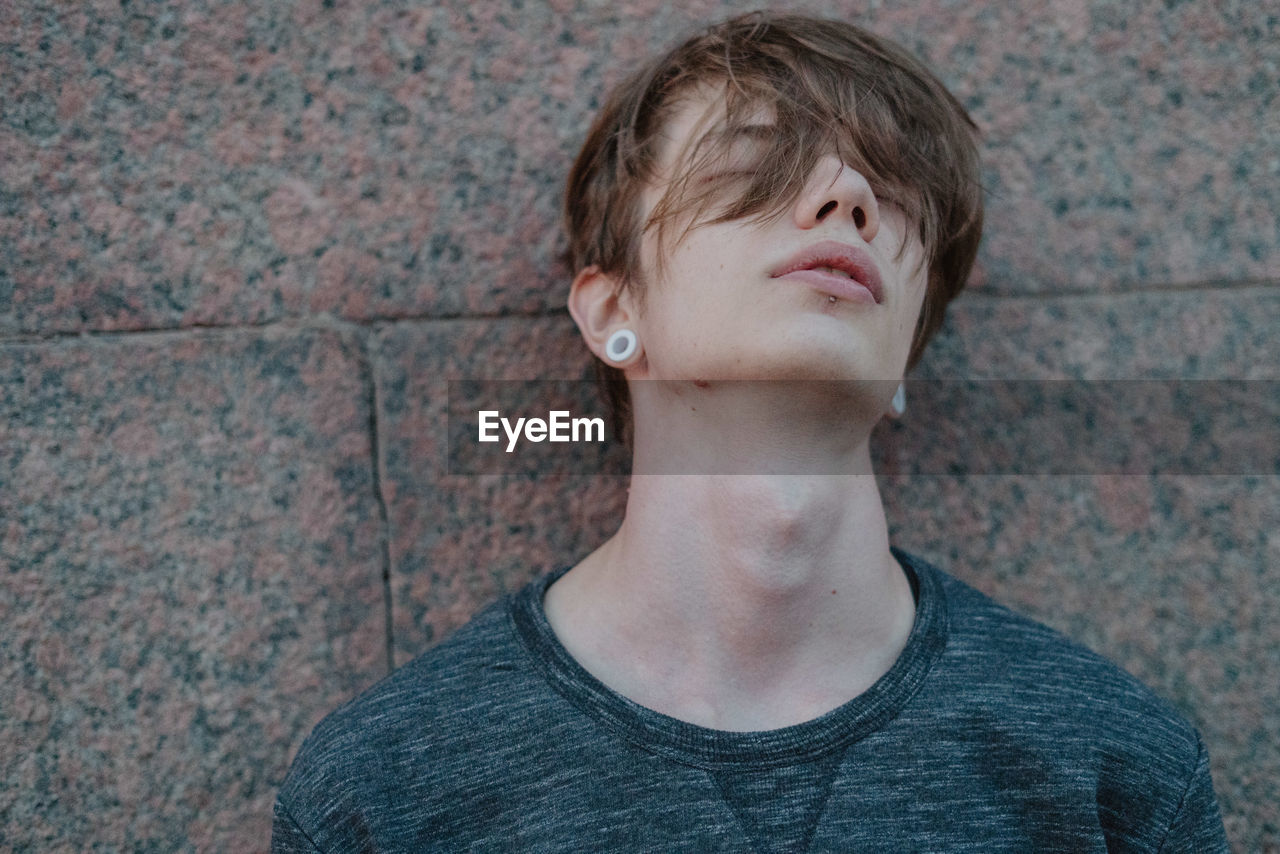 Close-up of young man leaning on wall