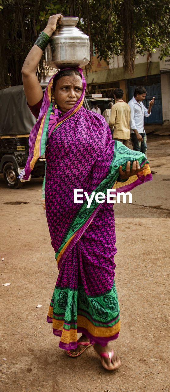 FULL LENGTH PORTRAIT OF WOMAN STANDING AGAINST MULTI COLORED UMBRELLA