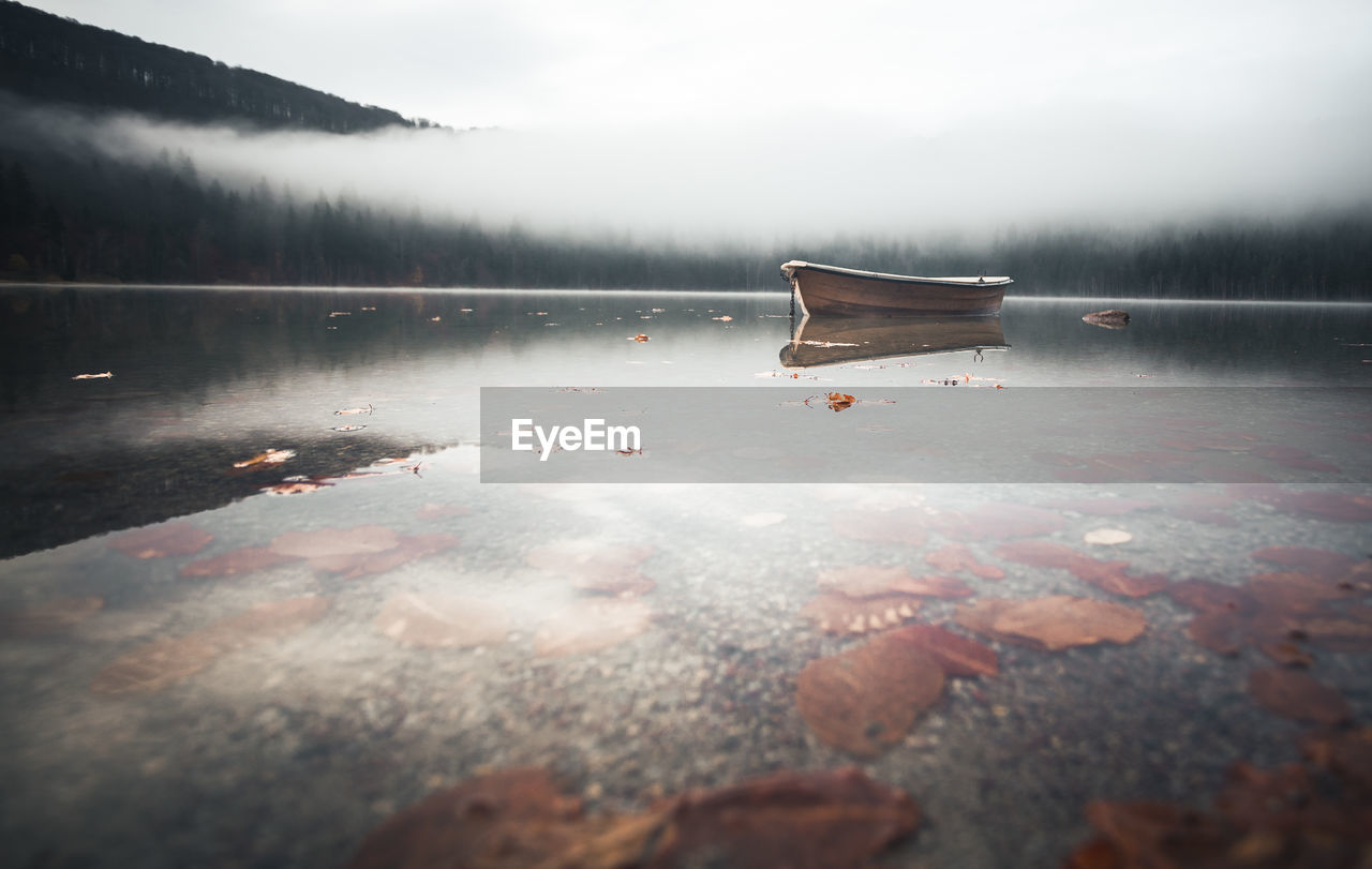 Boat moored in lake during foggy weather