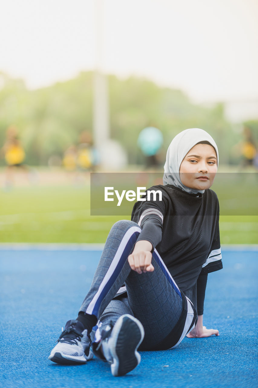 Thoughtful female athlete stretching at stadium