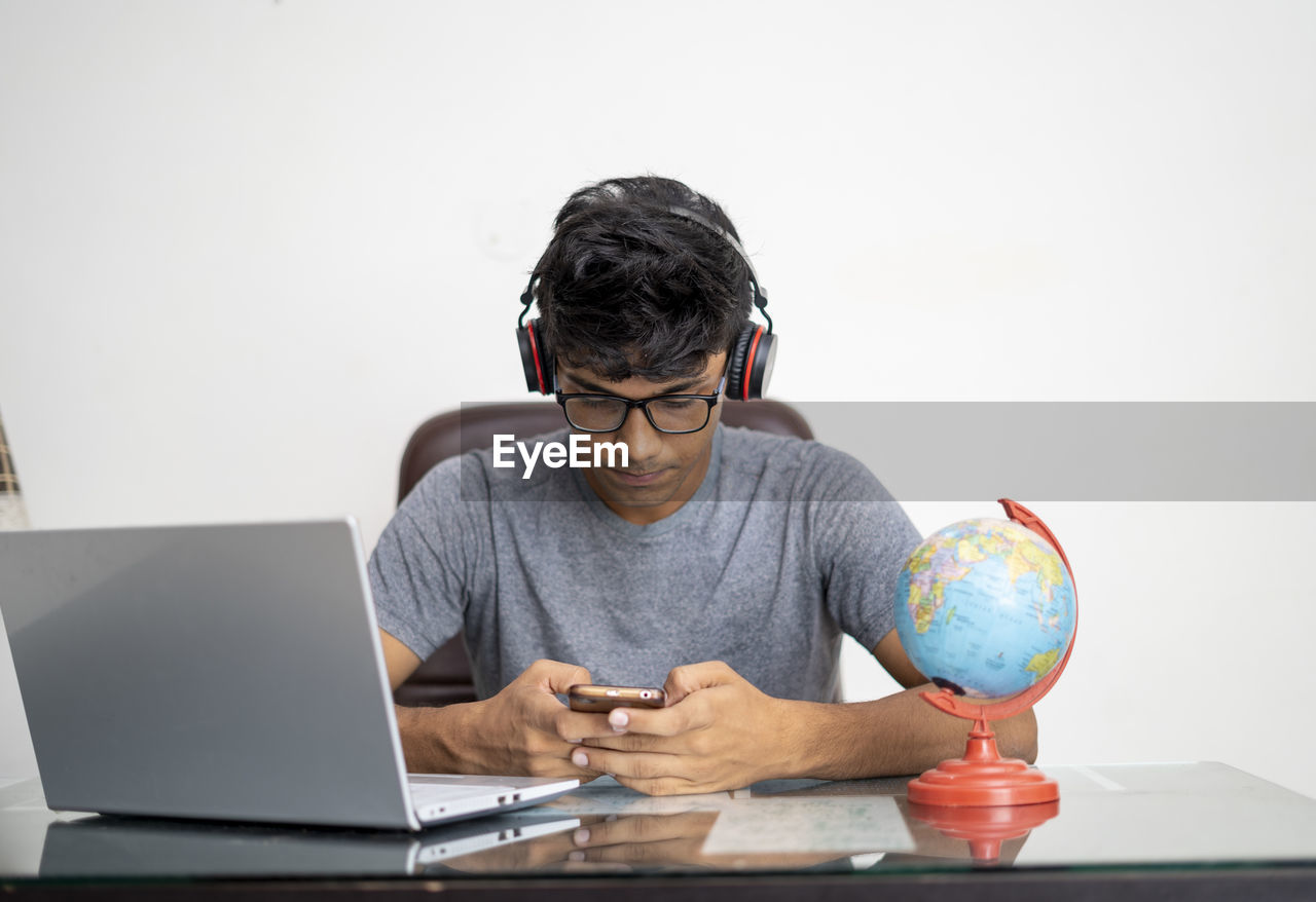 MAN USING MOBILE PHONE WHILE SITTING IN TABLE