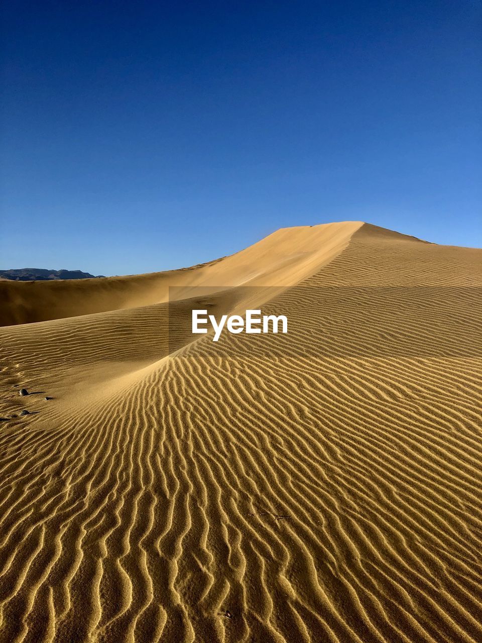 Sand dunes in desert against clear blue sky