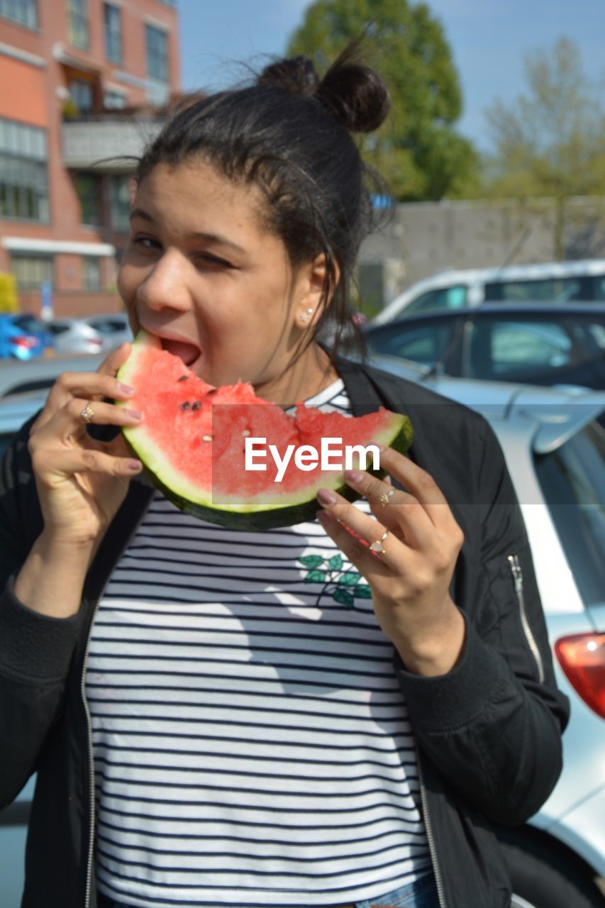 Young woman eating watermelon in city