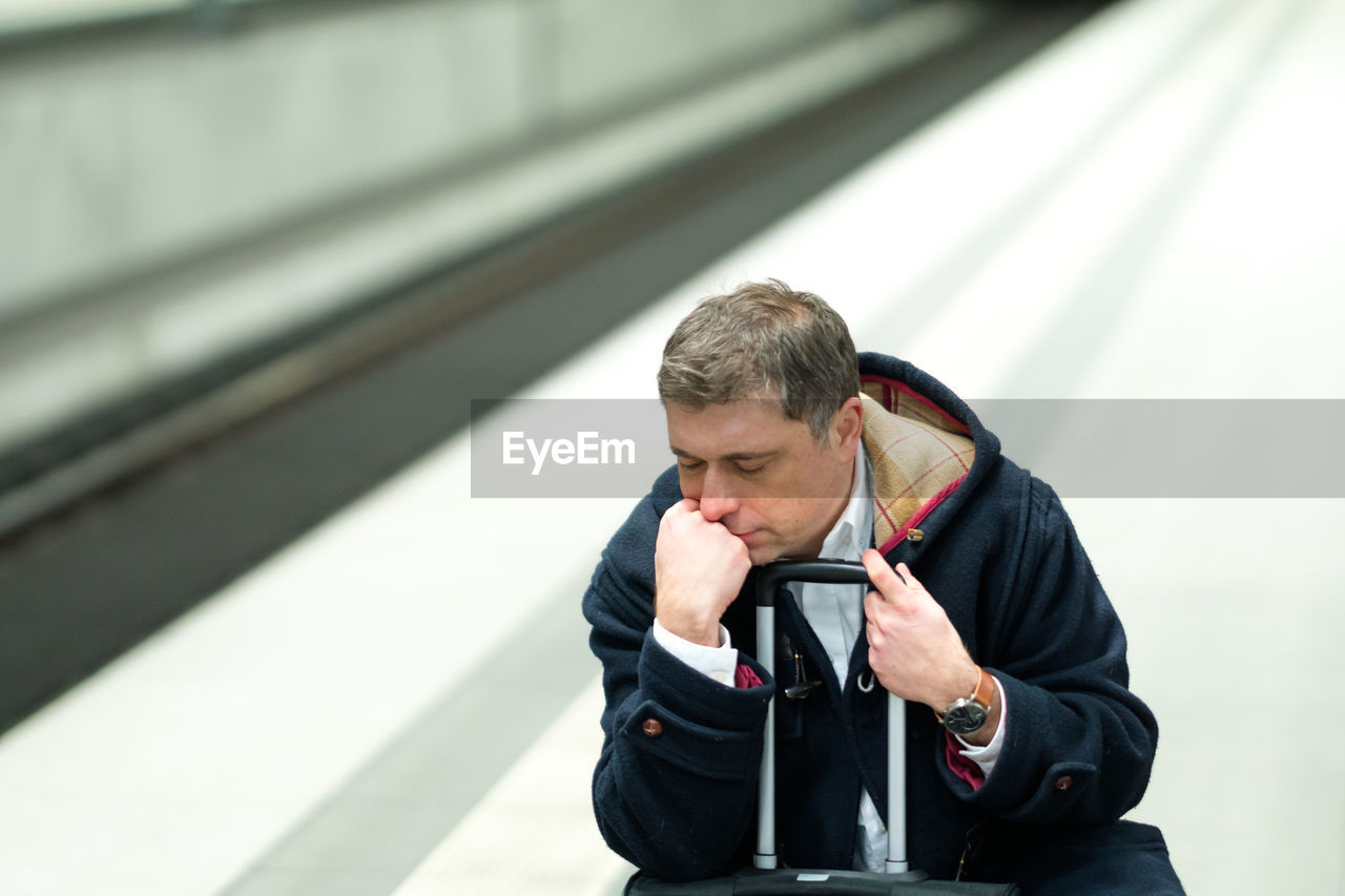 Man with luggage sleeping at railroad station platform