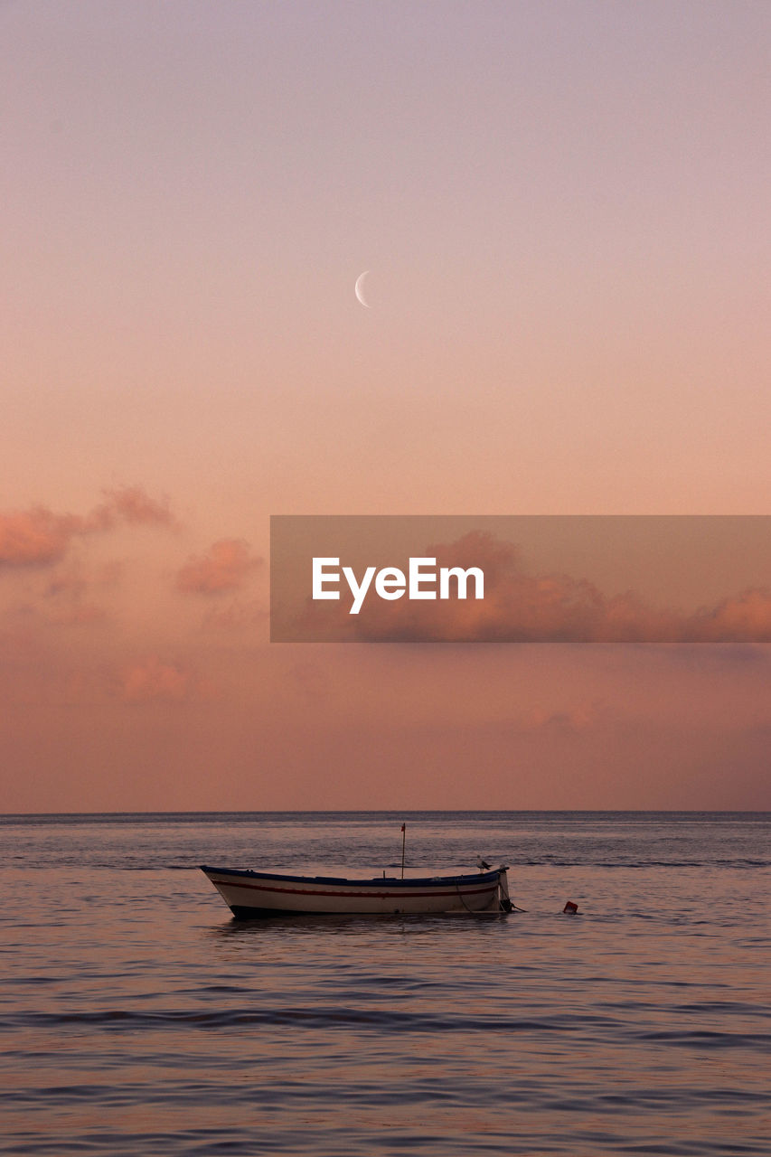 Boat in sea against sky during sunset