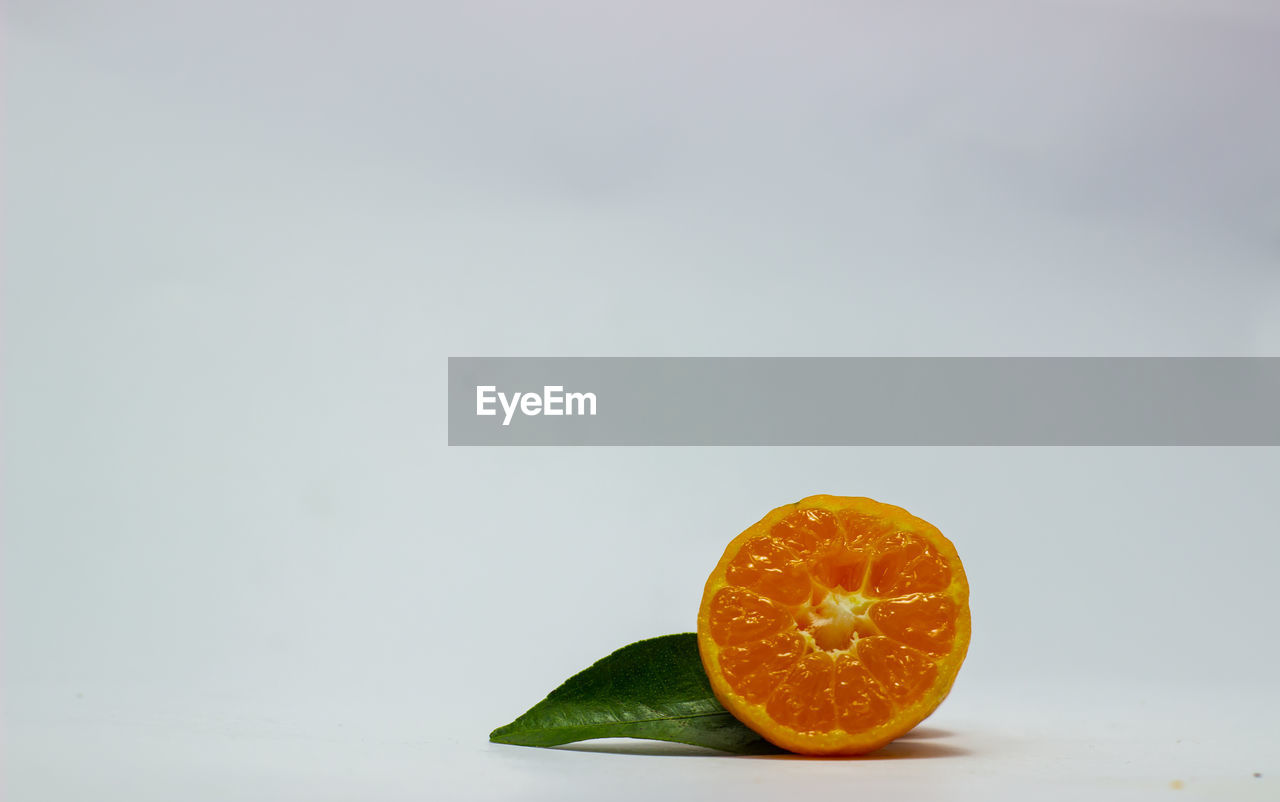 CLOSE-UP OF ORANGE FRUIT ON WHITE BACKGROUND