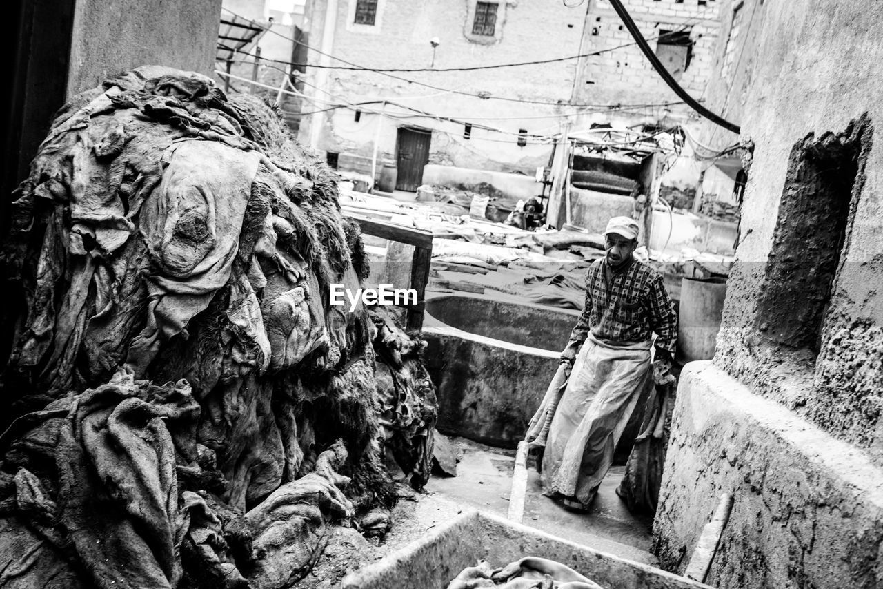 Worker walking by heap of clothes against building at laundry