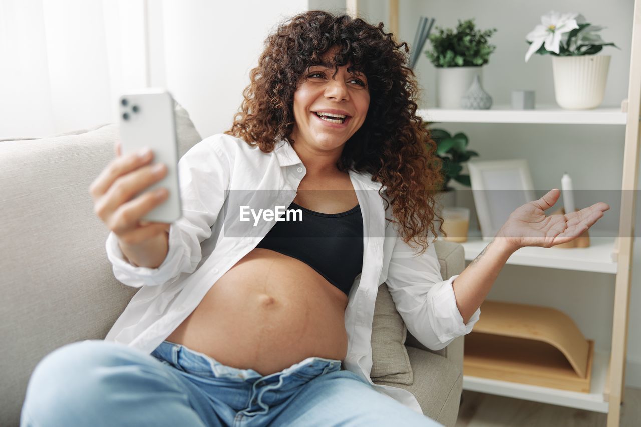 portrait of young woman using mobile phone while sitting at home