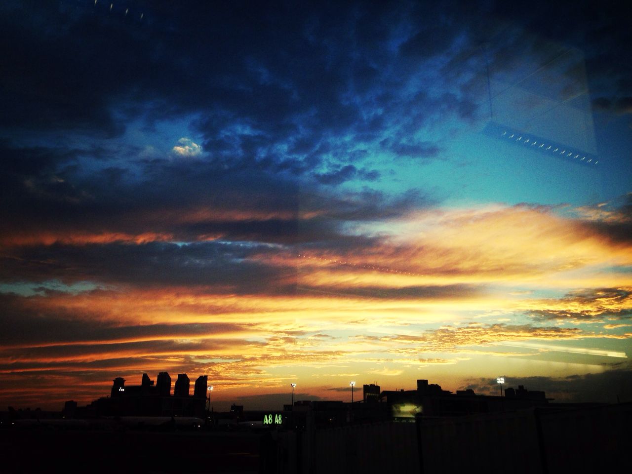 Silhouette city against cloudy sky at sunset