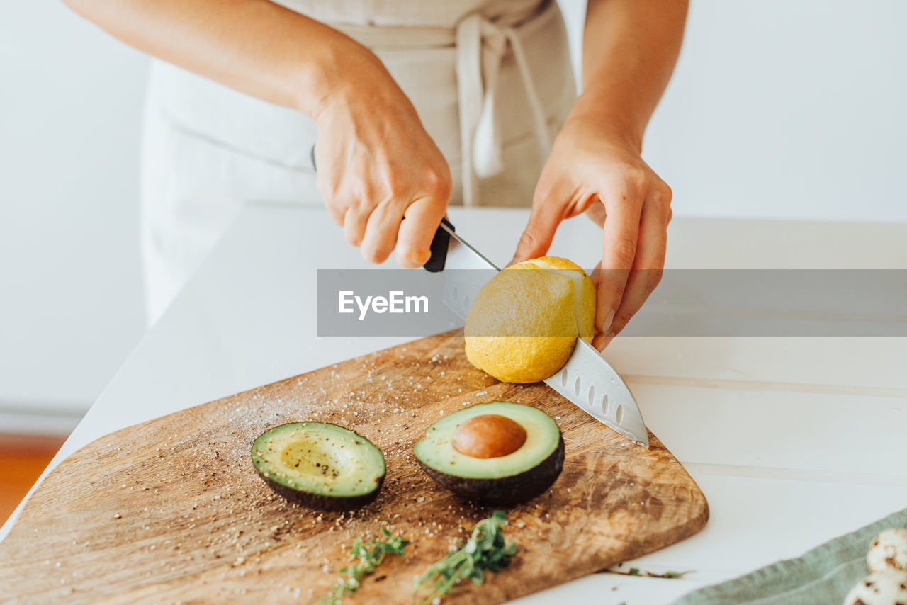 Female hands cutting lemon on a cutting board