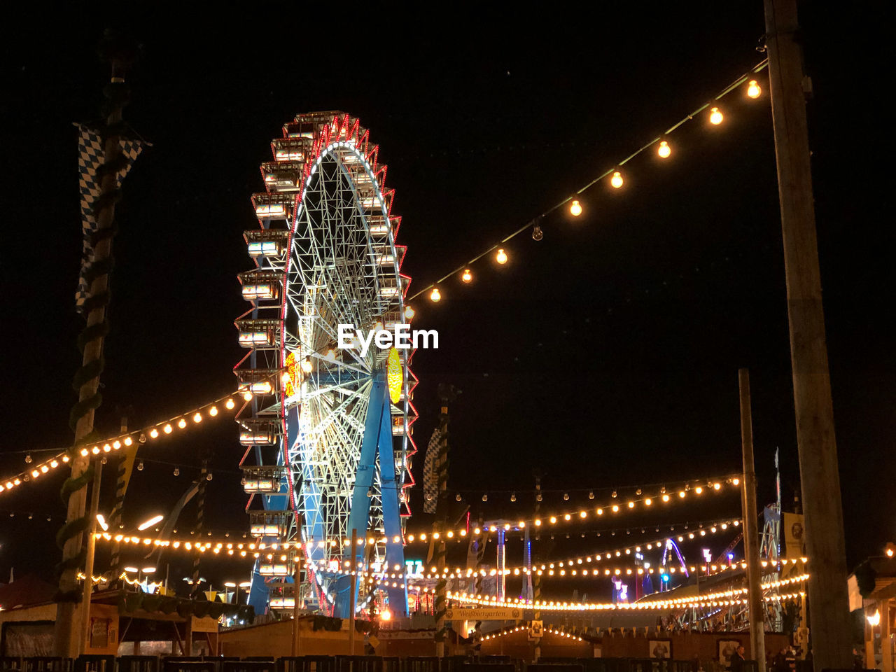 LOW ANGLE VIEW OF ILLUMINATED FERRIS WHEEL AGAINST SKY