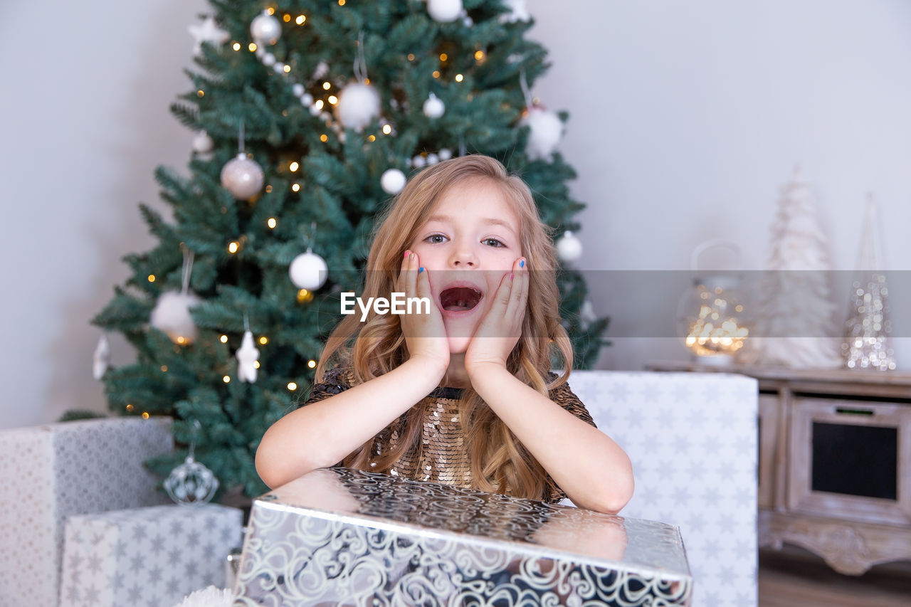 Portrait of girl with christmas tree at home