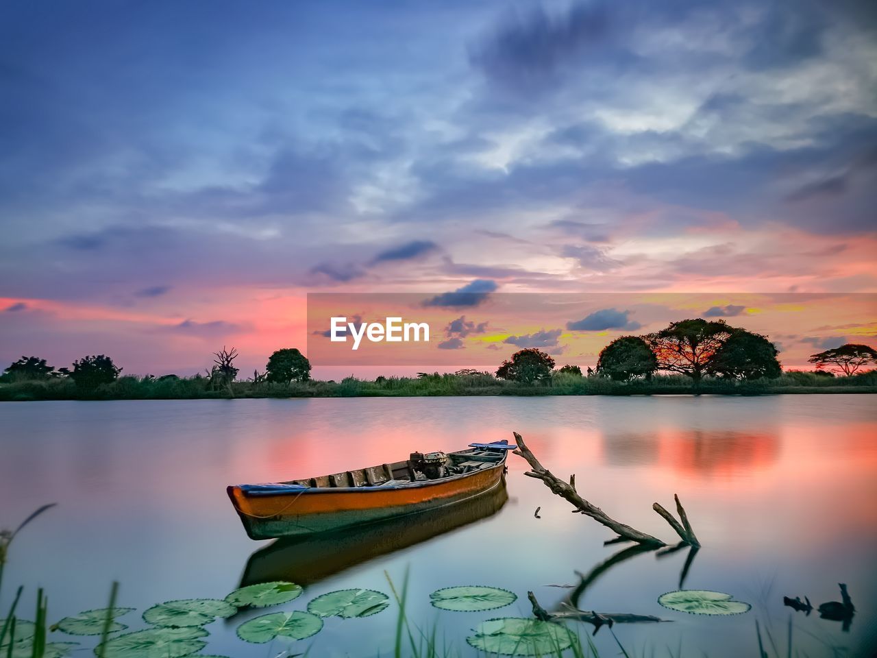 BOAT MOORED IN LAKE DURING SUNSET