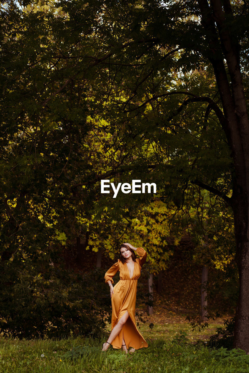 Full length of woman standing by tree