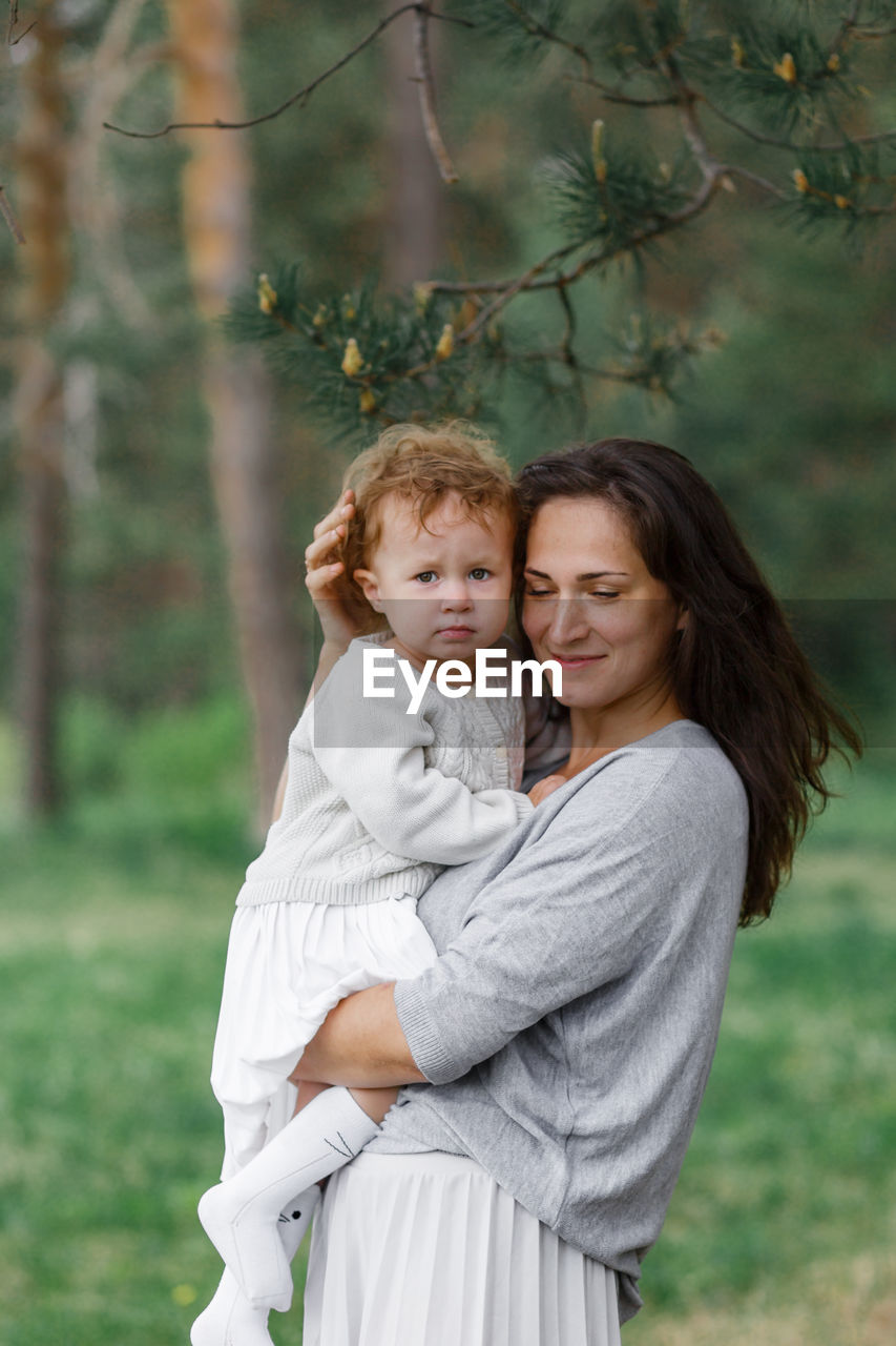 Portrait of happy girl with children standing against plants