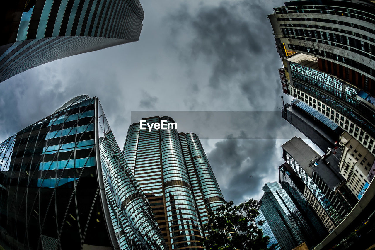 low angle view of skyscrapers against cloudy sky
