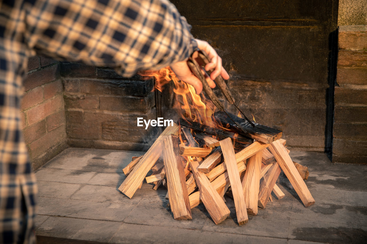 Man preparing barbecue grill with a burning wood pyre. male cooking meat on bbq fire in a summer day