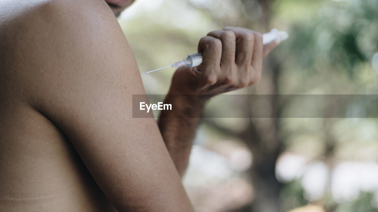 Midsection of man holding syringe