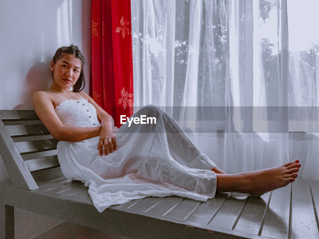 Portrait of young woman sitting by window at home