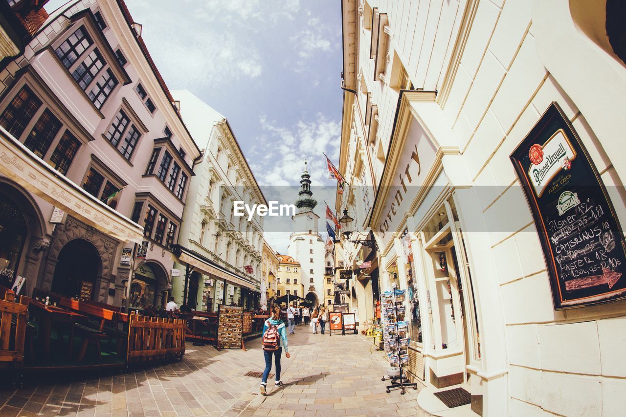 Rear view of woman walking on street amidst buildings