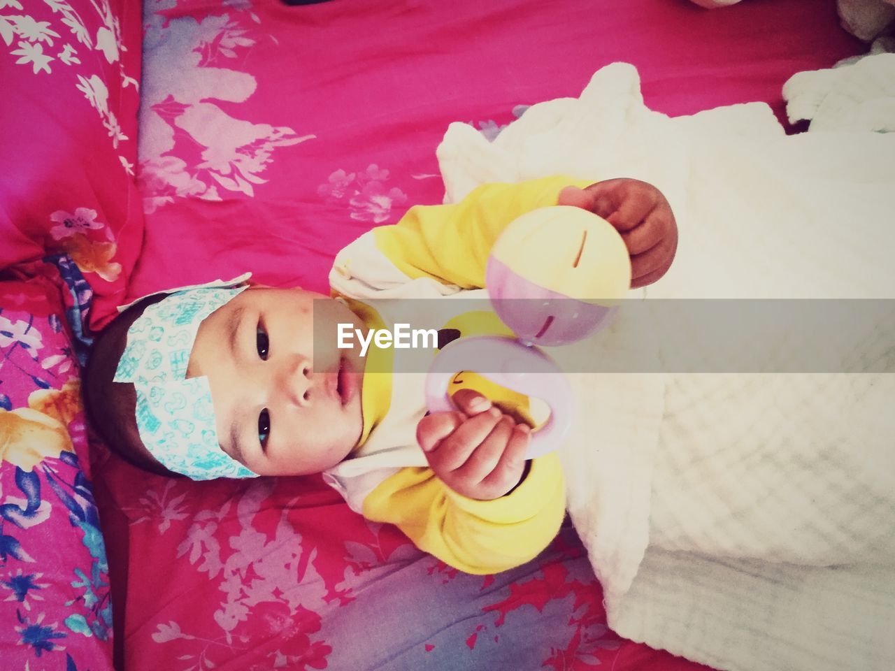 Portrait of baby with toy lying down on bed