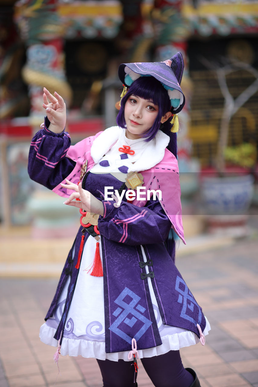 portrait of young woman wearing traditional clothing standing in city