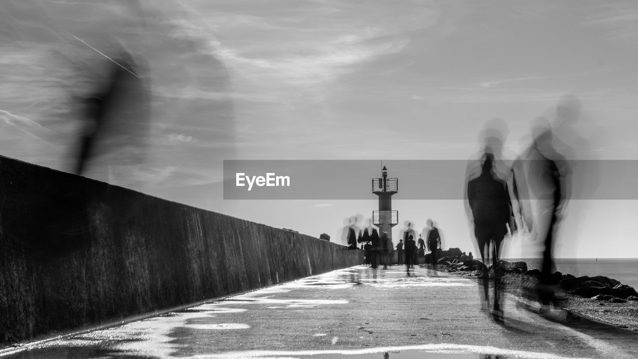 People on pier with lighthouse in perspective