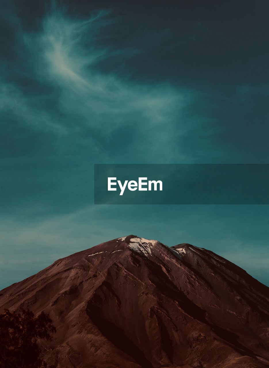 Low angle view of mountain against cloudy sky