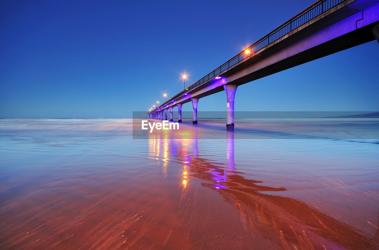 Pier over sea against clear sky at dusk