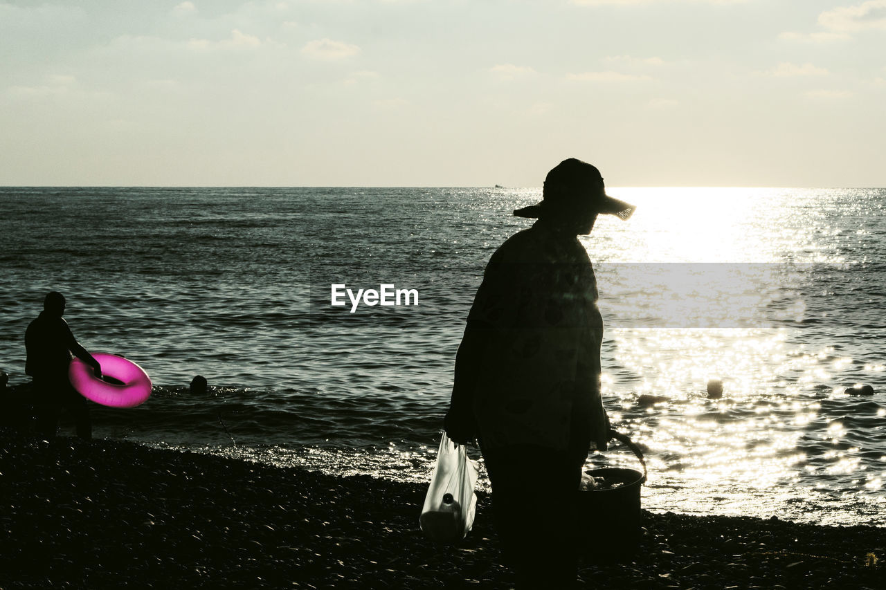 SILHOUETTE MAN STANDING ON BEACH AGAINST SEA AGAINST SKY