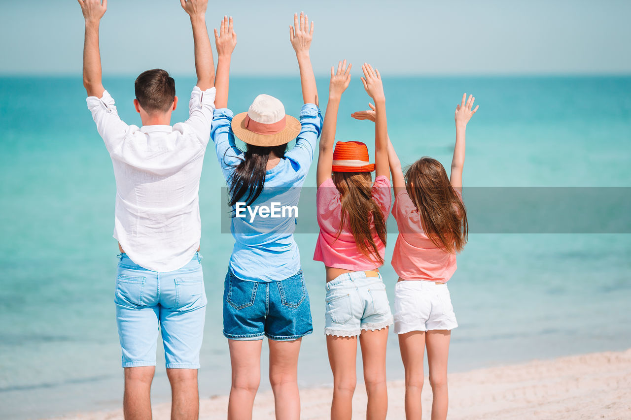 Rear view of people at beach against sky