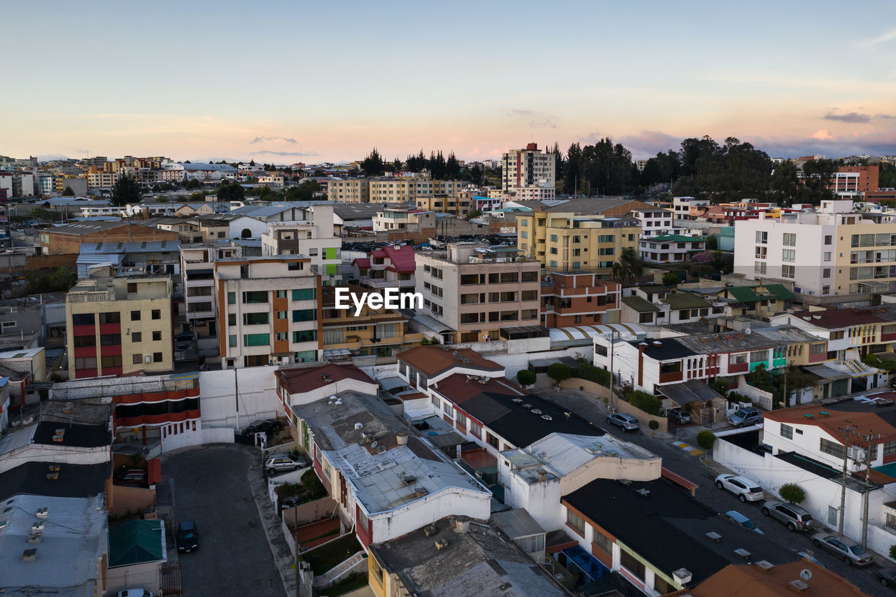 HIGH ANGLE VIEW OF BUILDINGS AGAINST SKY DURING SUNSET