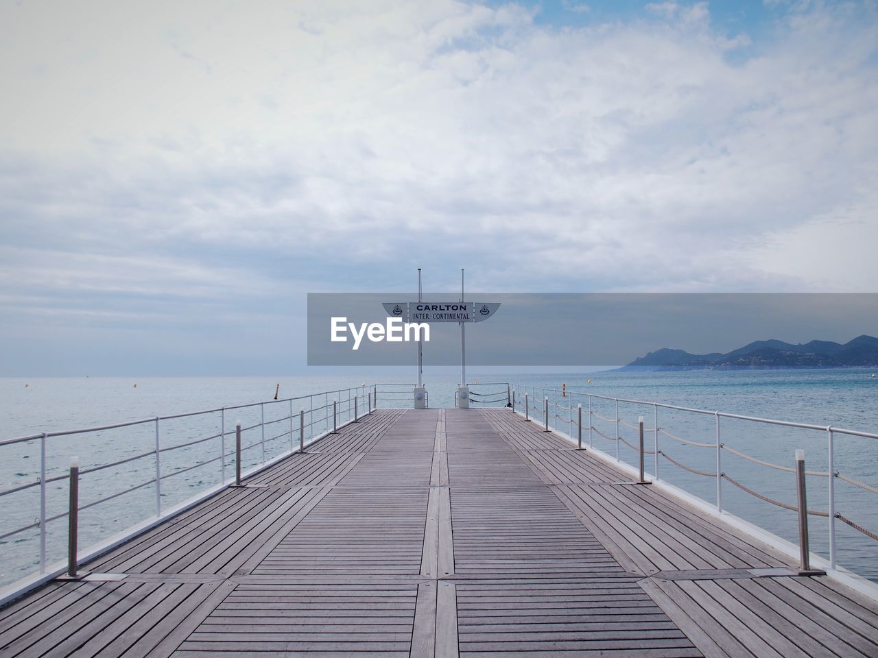 Pier on sea against cloudy sky