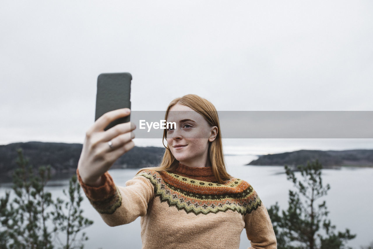 Smiling young woman taking selfie