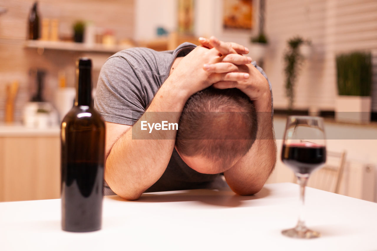 cropped hand of man holding wineglass on table