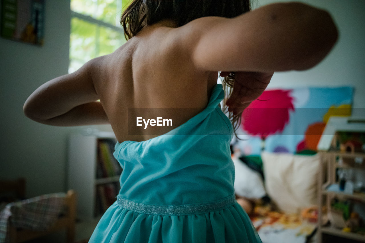 Child putting on teal tulle dress