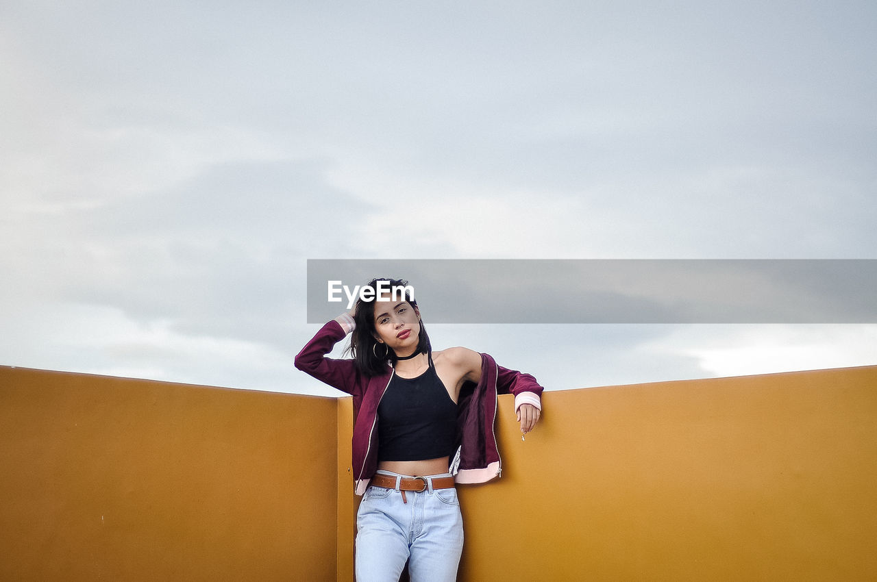 YOUNG WOMAN STANDING AGAINST SKY