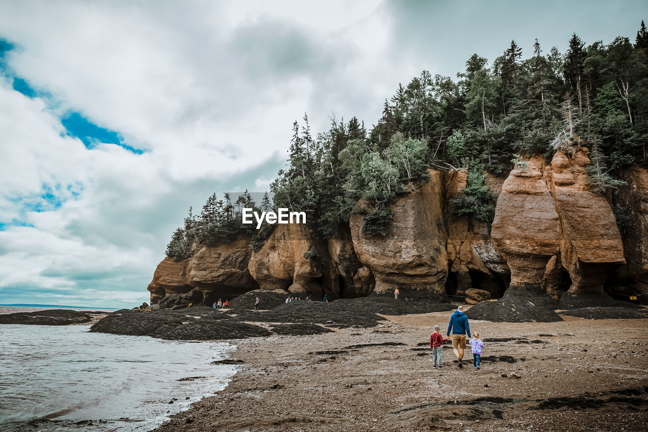 Father and children walking by the river on a cloudy day