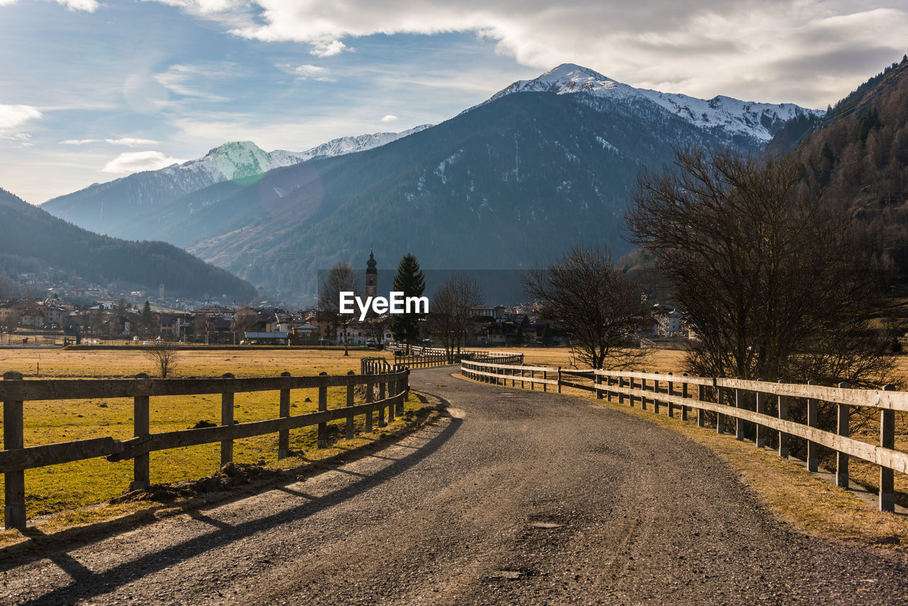 Road leading towards snowcapped mountains against sky and mountains.