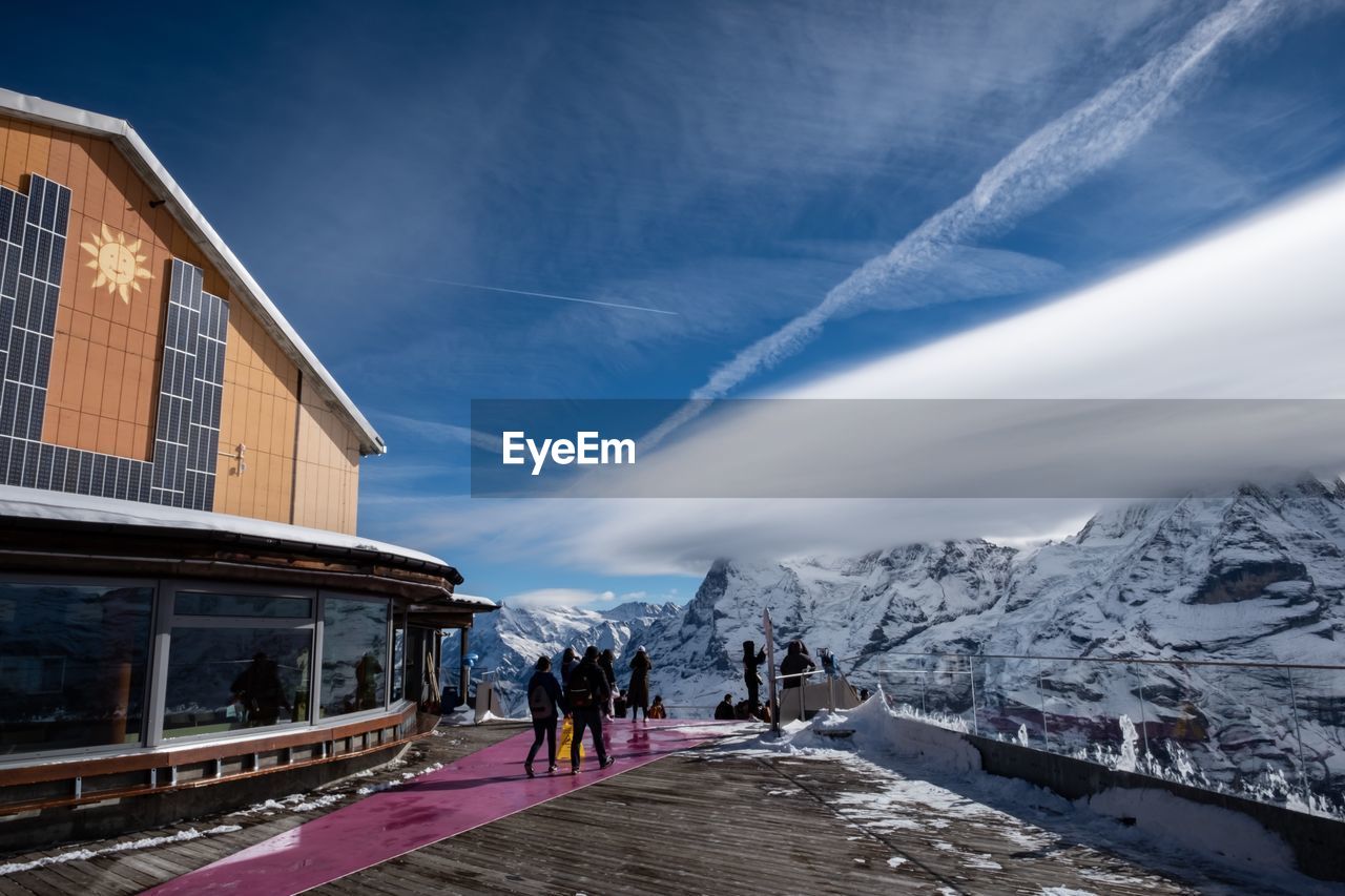 People on snowcapped mountain against sky