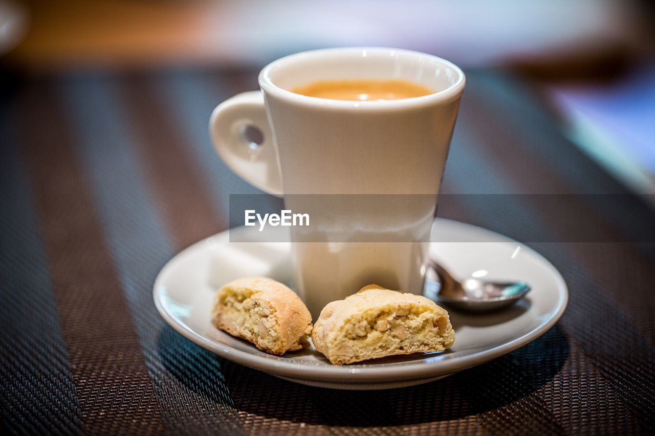 CLOSE-UP OF COFFEE CUP AND COOKIES ON TABLE