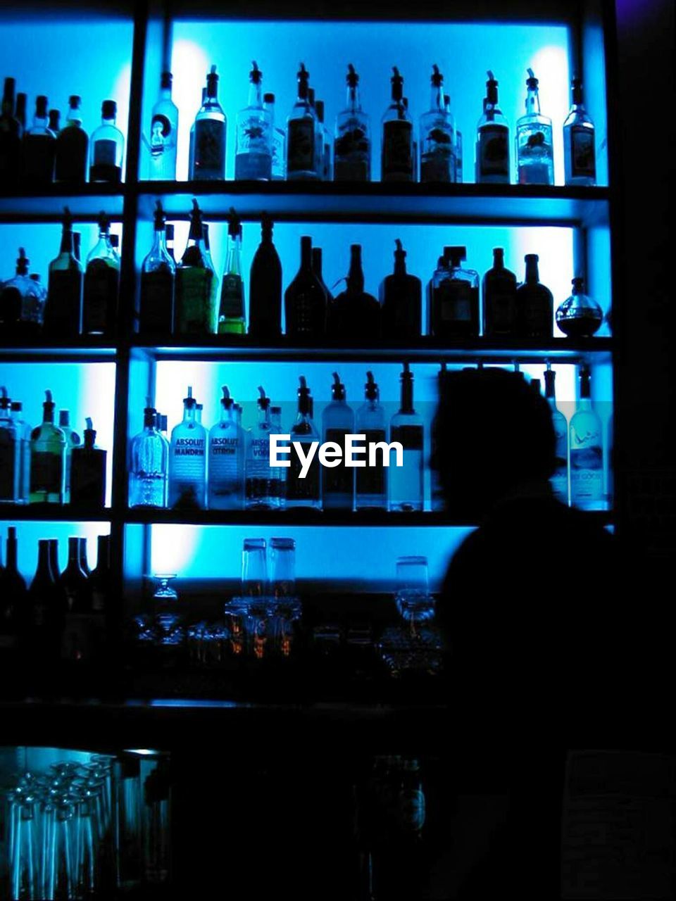 Silhouette man against bottles in shelf