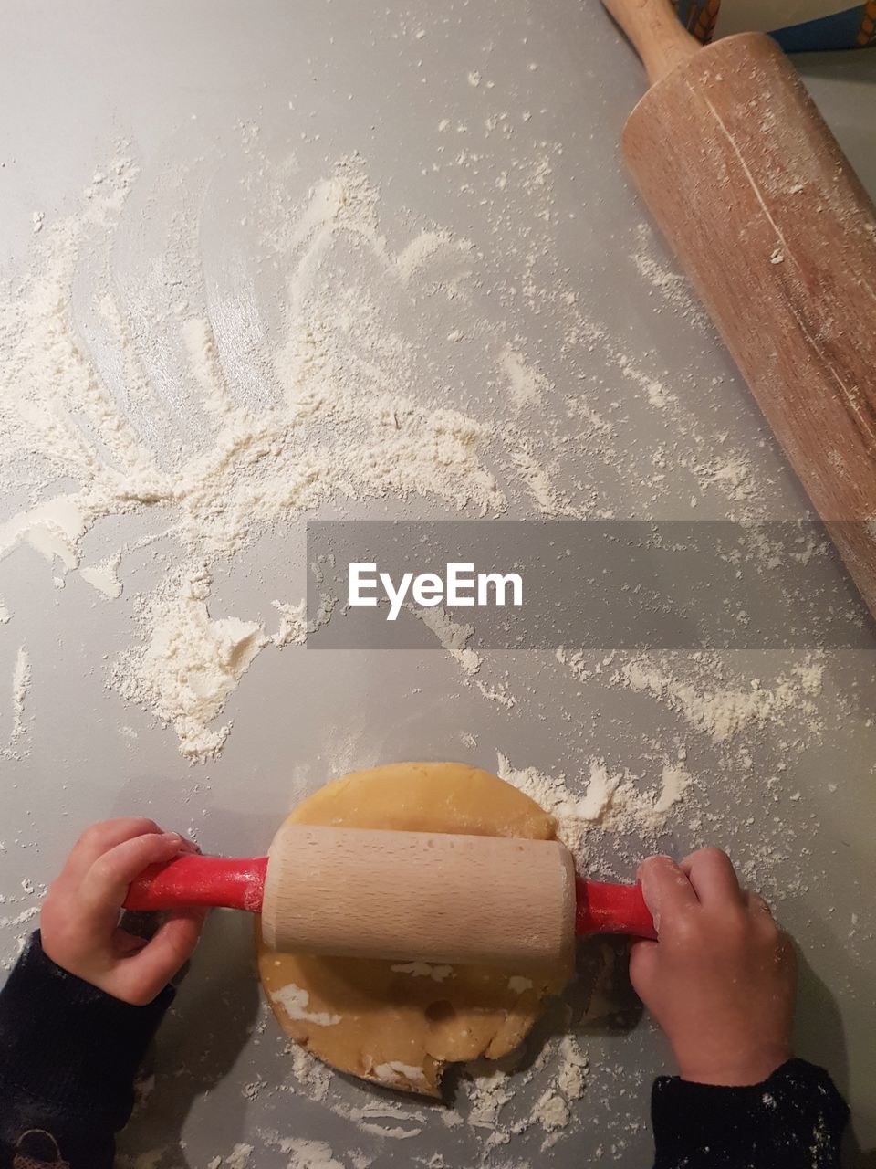 Cropped hands of person rolling pin on dough