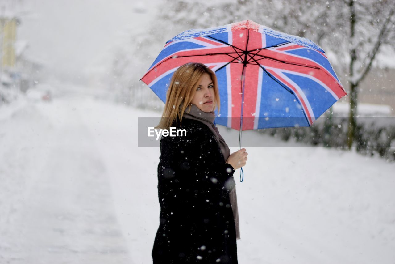 Woman with umbrella standing in snow
