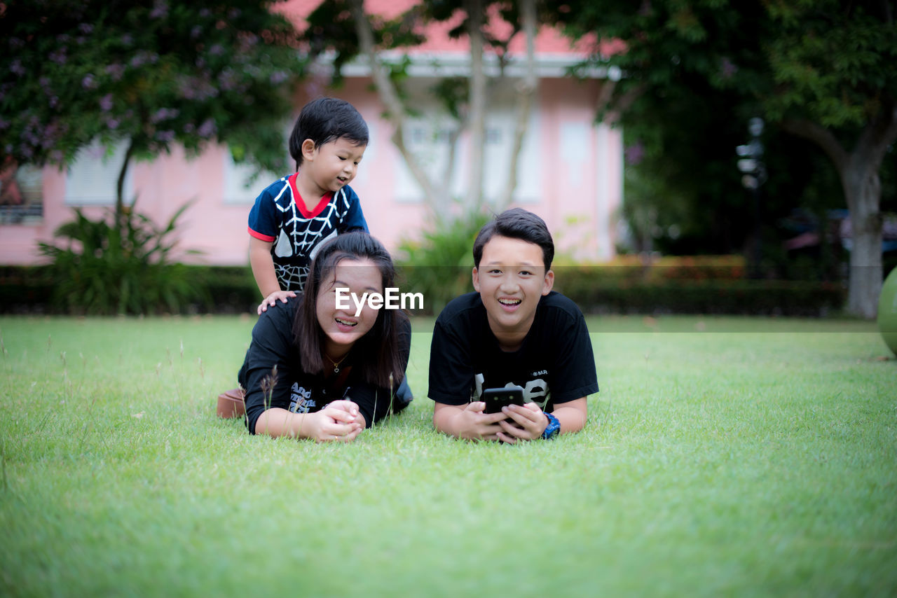 Siblings lying on grassy land in park