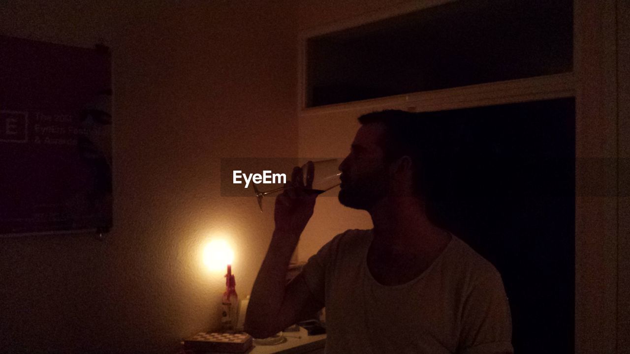 Man having wine in dark room at home