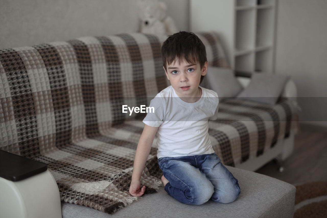 Boy toddler sad on the couch in the real room at home, lifestyles