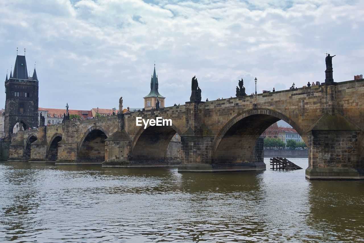 Bridge over river in city against sky