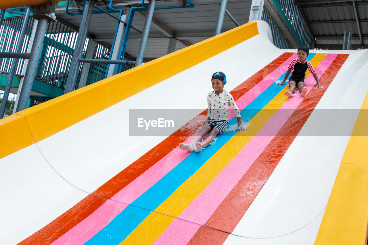 HIGH ANGLE VIEW OF CHILDREN PLAYING WITH MULTI COLORED UMBRELLA